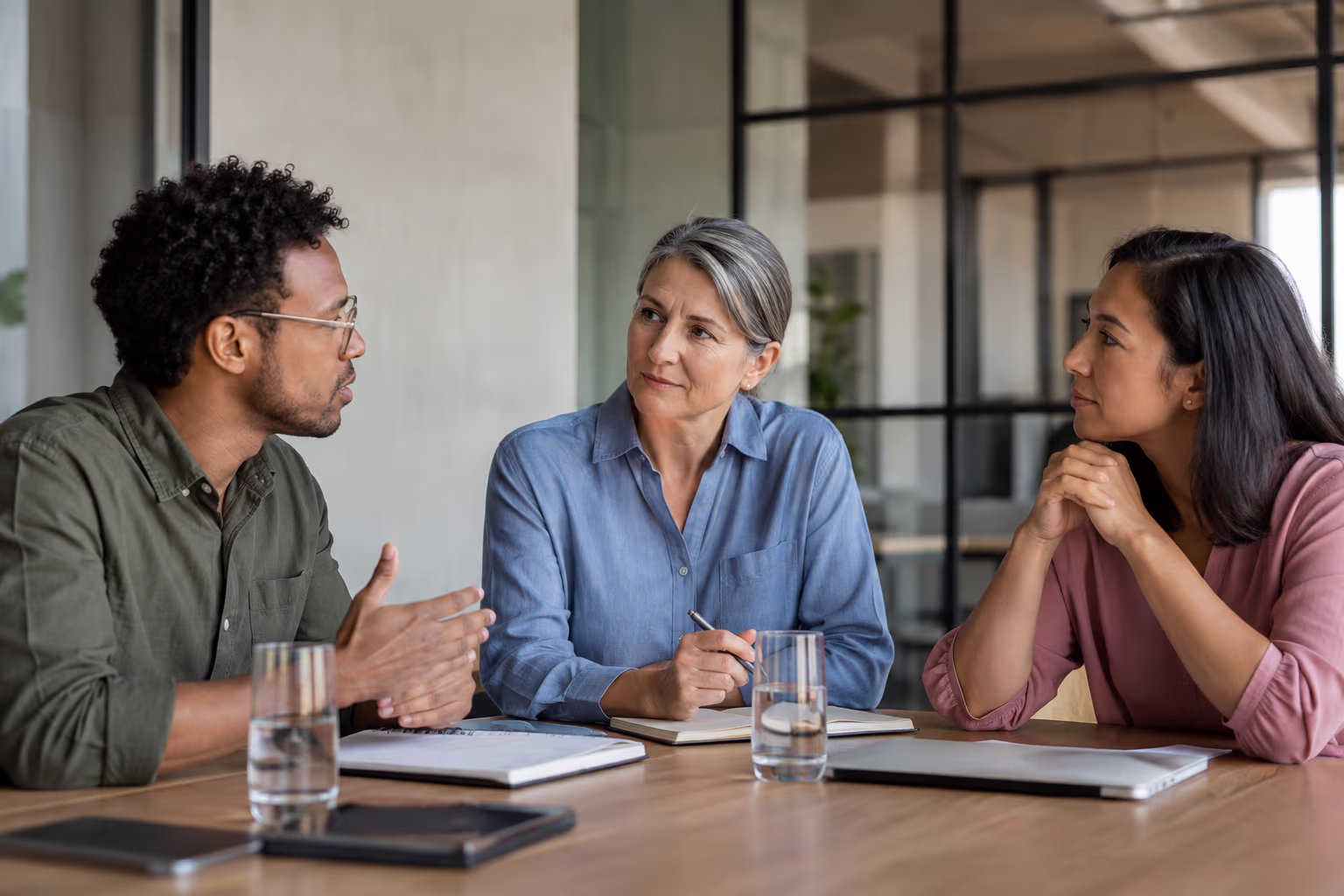 A neutral facilitator listening as two coworkers discuss a concern