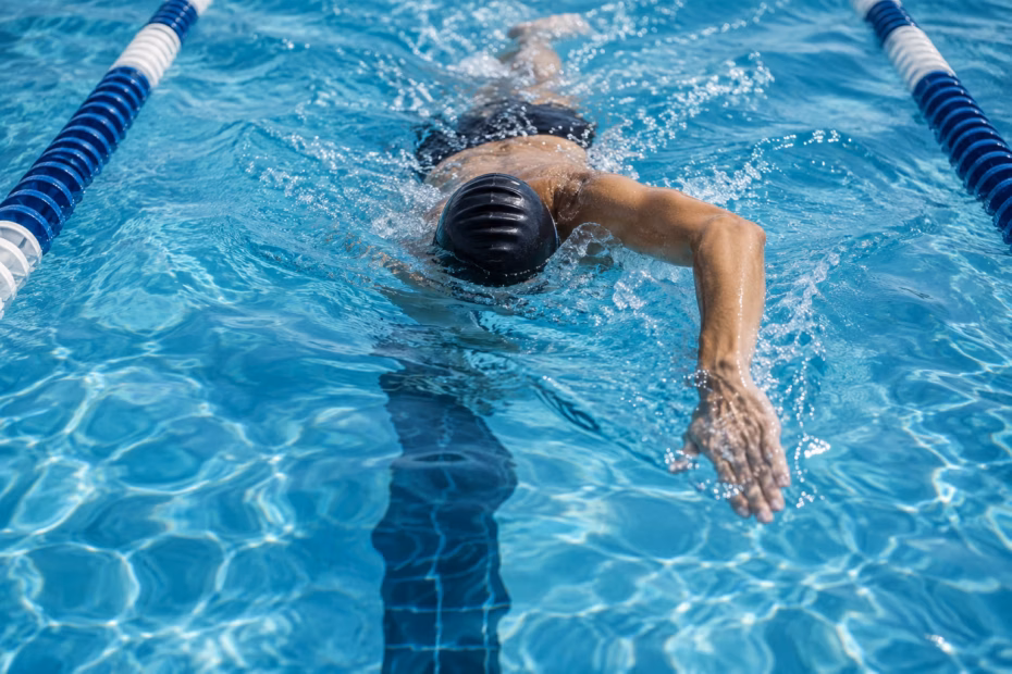 A swimmer making a smooth stroke in a clear blue lap pool