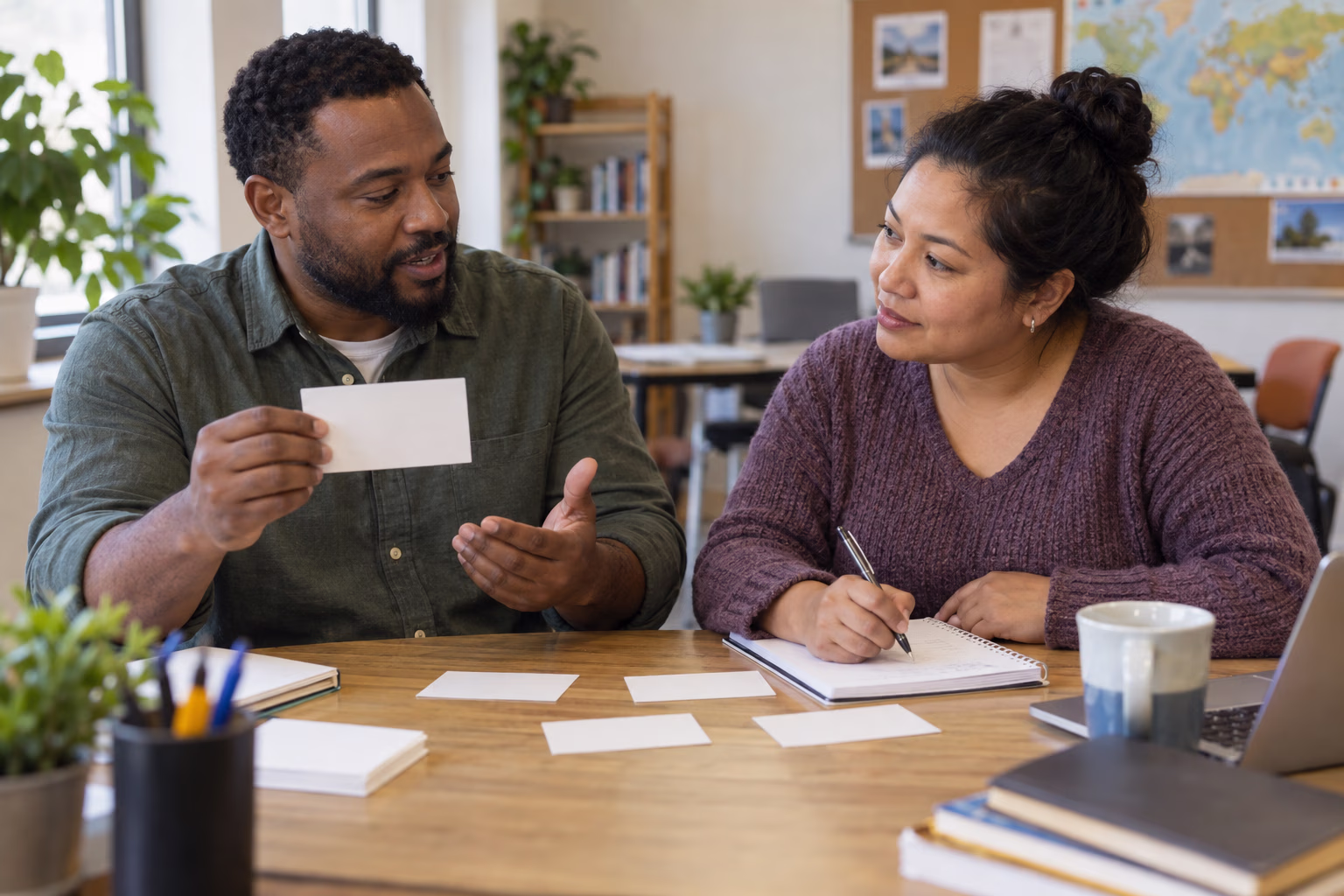 Two adult learners practice English together with blank cards and a notebook