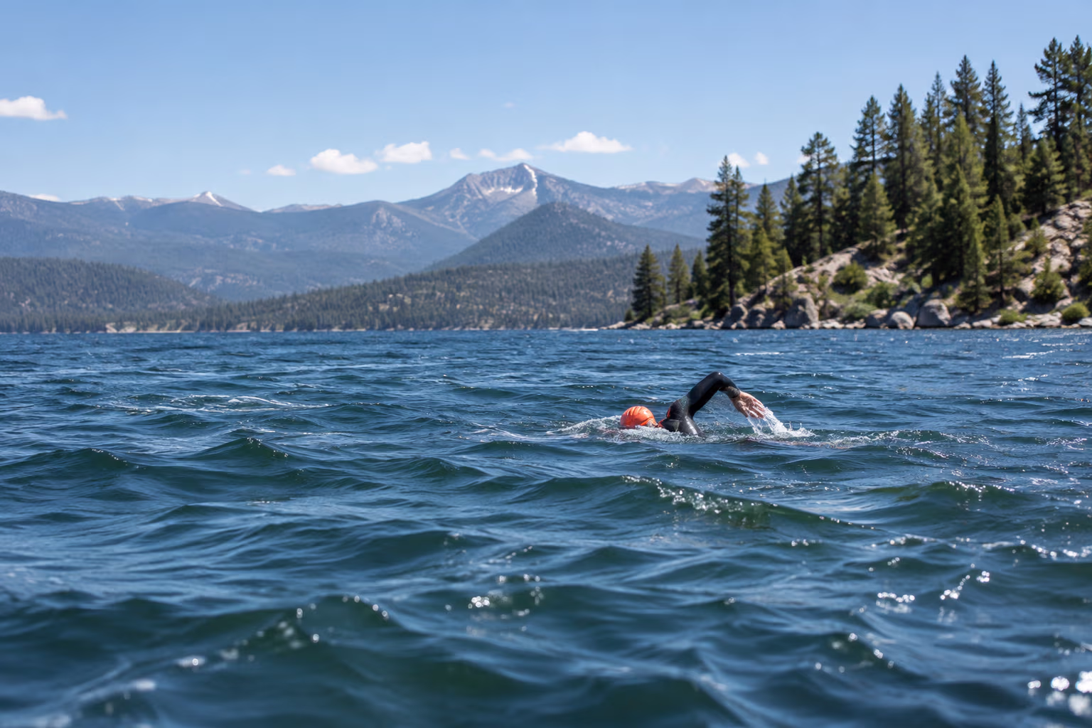 An open-water swimmer crossing a lake with small choppy waves
