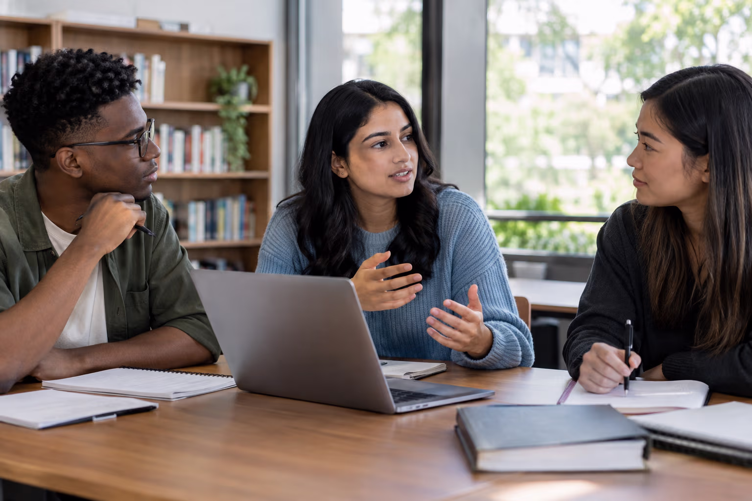 Three students discussing a group project and listening to one another